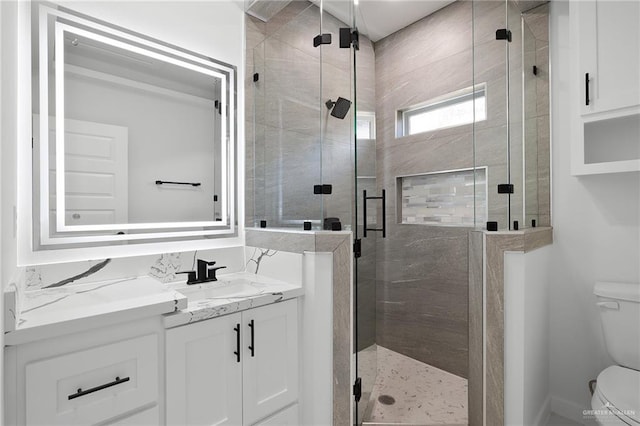 bathroom featuring vanity, toilet, and a shower with shower door