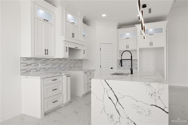 kitchen with white cabinets, light stone counters, and sink