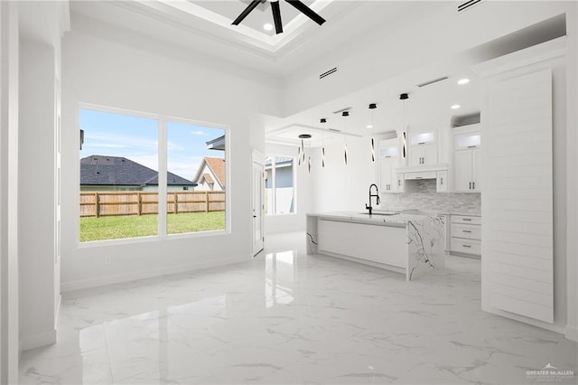 kitchen with backsplash, ceiling fan, sink, pendant lighting, and white cabinetry