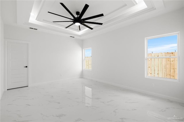 spare room featuring a raised ceiling and ceiling fan