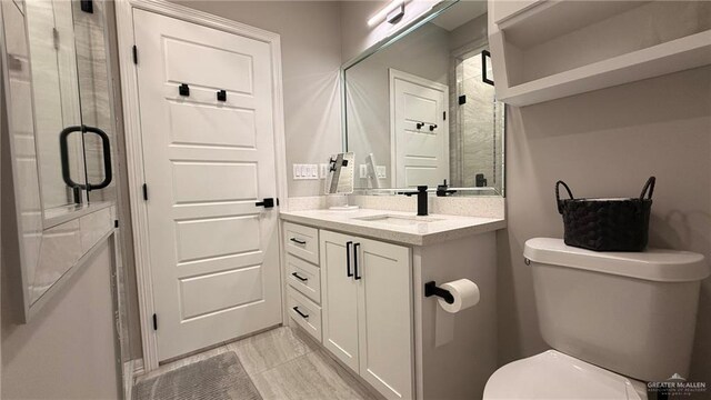 bathroom featuring vanity, toilet, and a shower with door