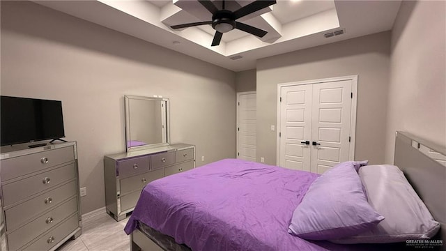 bedroom featuring ceiling fan, a closet, and a tray ceiling