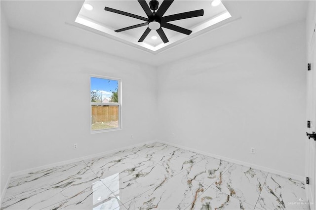 empty room with marble finish floor, recessed lighting, a ceiling fan, a tray ceiling, and baseboards