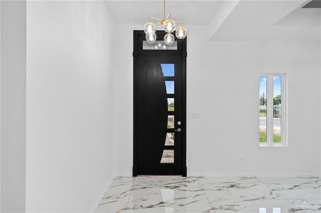 foyer entrance featuring baseboards, marble finish floor, and a notable chandelier