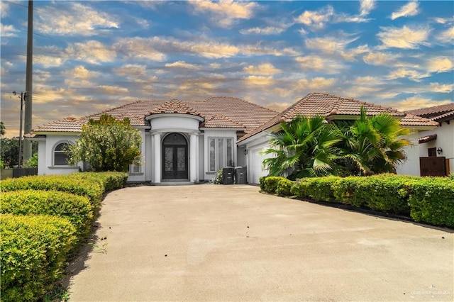 mediterranean / spanish home with a garage and french doors