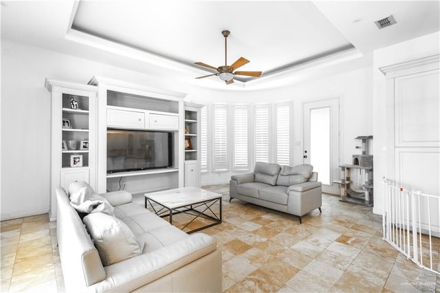 living room with a raised ceiling and ceiling fan