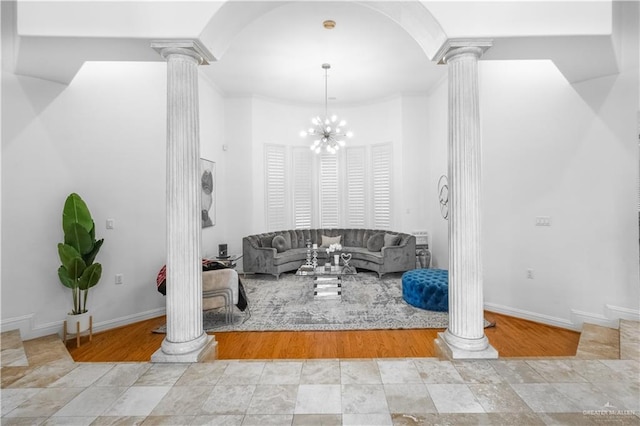 unfurnished living room with light wood-type flooring, ornate columns, and a chandelier