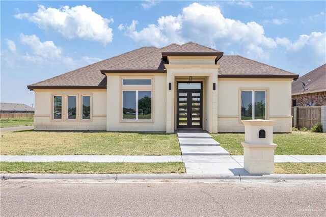 2400 Windmill Palm, Rio Grande City, TX 78582 - prairie-style home featuring stucco siding, roof with shingles, fence, and a front yard