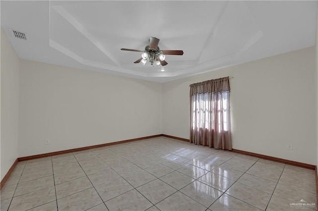 unfurnished room featuring a raised ceiling, ceiling fan, and light tile patterned flooring