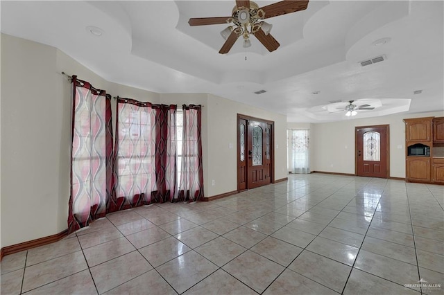 entrance foyer with a tray ceiling, a wealth of natural light, and ceiling fan