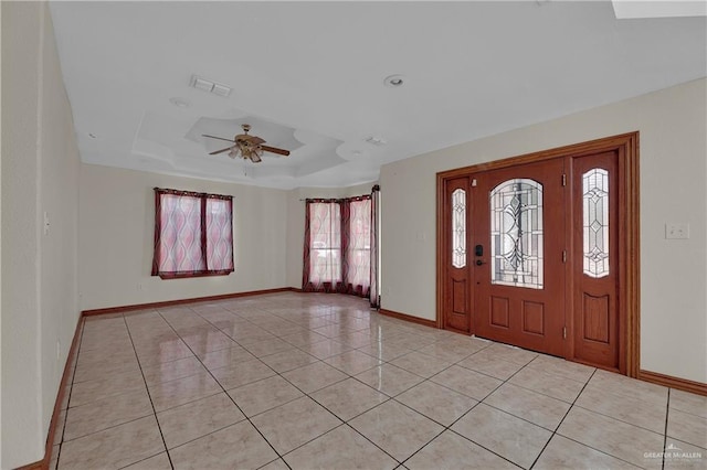 tiled foyer entrance with a tray ceiling and ceiling fan