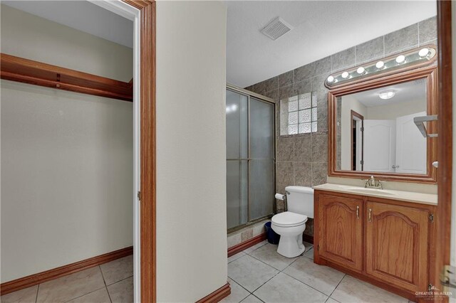 bathroom with vanity, a shower with shower door, tile walls, and toilet