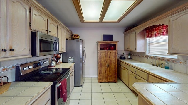 kitchen with backsplash, tile counters, sink, and stainless steel appliances