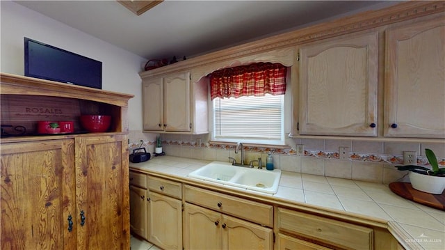 kitchen with backsplash, tile countertops, sink, and light brown cabinets