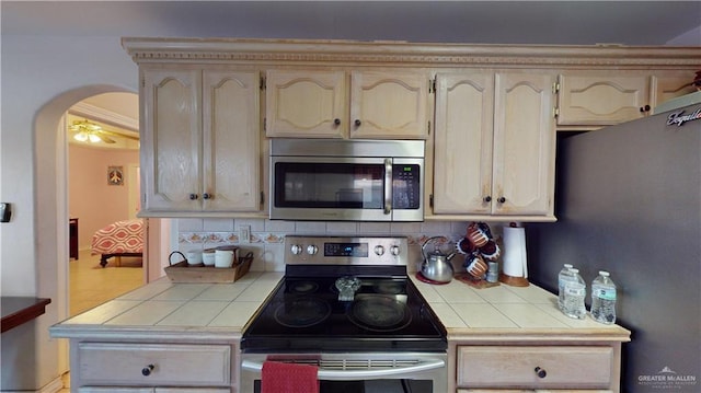 kitchen with backsplash, ceiling fan, tile counters, and stainless steel appliances