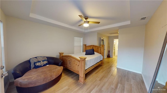 bedroom with light hardwood / wood-style floors, a raised ceiling, and ceiling fan