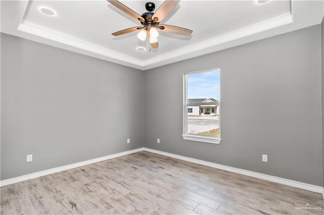 unfurnished room with a raised ceiling, ceiling fan, and light hardwood / wood-style floors