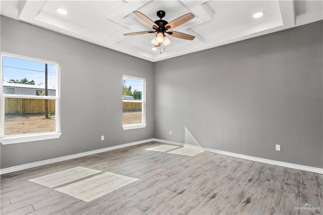 empty room featuring ceiling fan, a raised ceiling, and light wood-type flooring