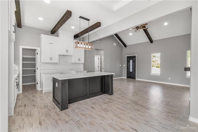 kitchen featuring white cabinetry, a center island, hanging light fixtures, and light wood-type flooring