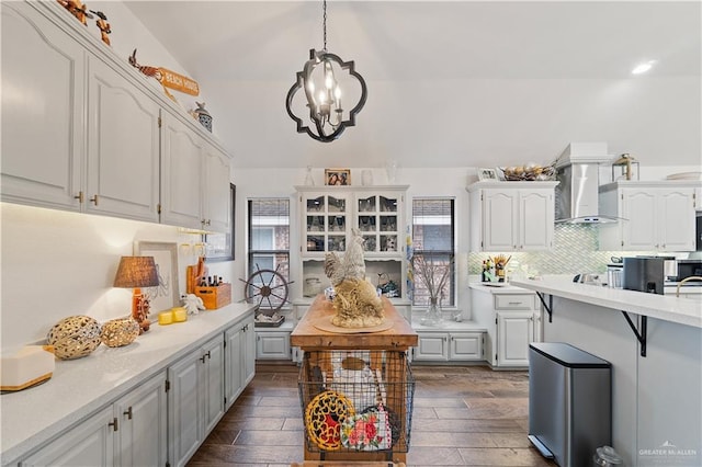 kitchen with decorative backsplash, wall chimney exhaust hood, decorative light fixtures, a notable chandelier, and white cabinetry