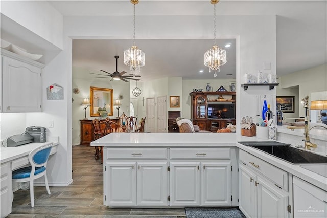 kitchen featuring white cabinets, ceiling fan with notable chandelier, pendant lighting, and kitchen peninsula