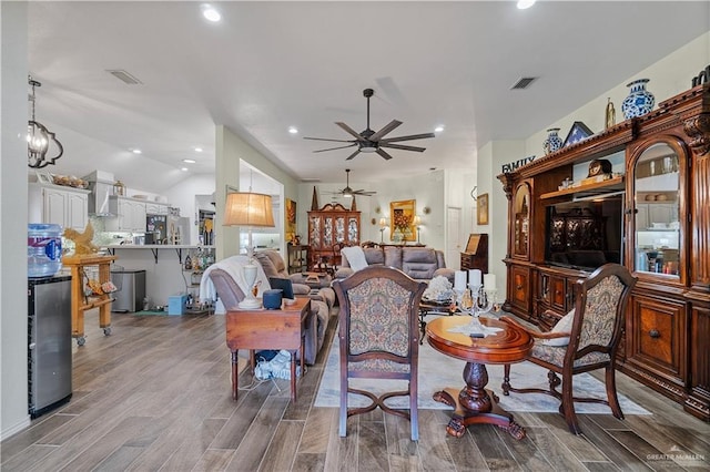 living room featuring ceiling fan with notable chandelier and lofted ceiling