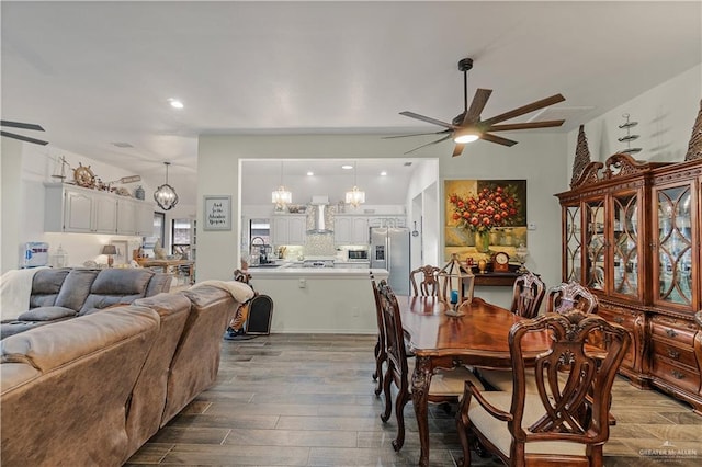 dining area featuring hardwood / wood-style floors, ceiling fan with notable chandelier, and sink