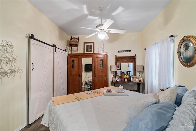 bedroom with a barn door, dark hardwood / wood-style floors, and ceiling fan