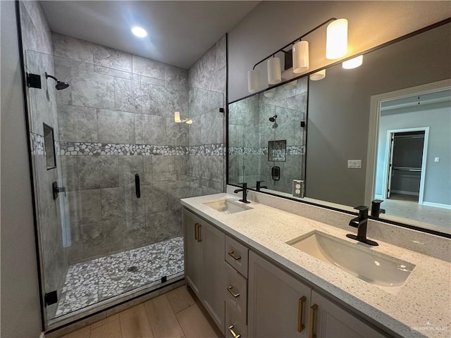 full bathroom with double vanity, a stall shower, and a sink