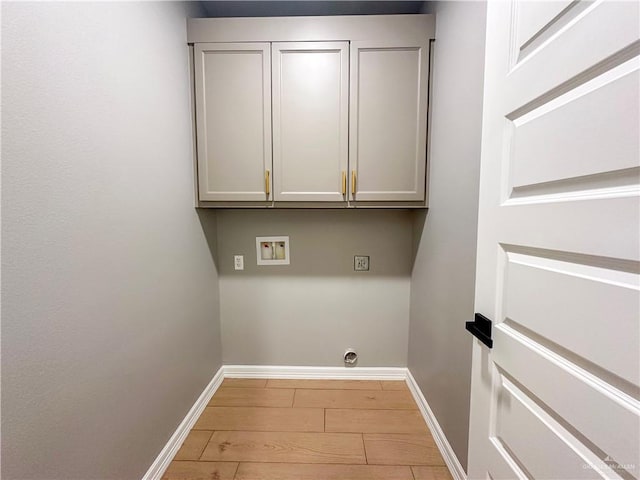 washroom with hookup for a washing machine, cabinet space, baseboards, and light wood-style floors