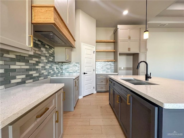 kitchen featuring light wood-style flooring, a sink, open shelves, tasteful backsplash, and custom range hood