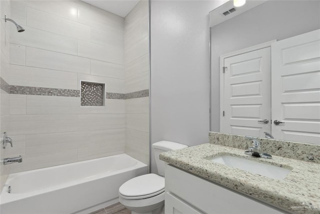 full bathroom with tiled shower / bath combo, vanity, and toilet