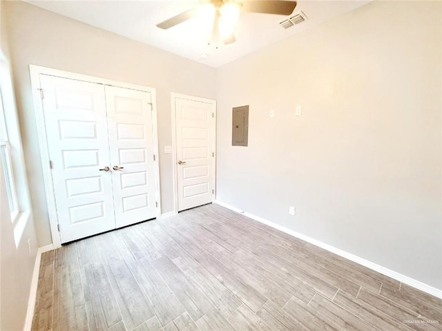 unfurnished bedroom with ceiling fan, electric panel, light hardwood / wood-style floors, and a closet