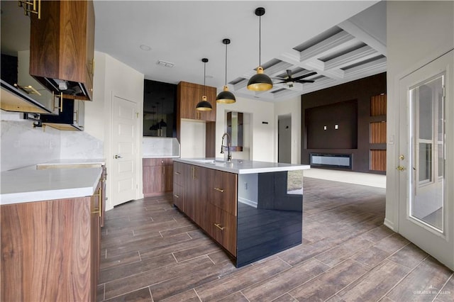 kitchen featuring ceiling fan, sink, coffered ceiling, beamed ceiling, and pendant lighting