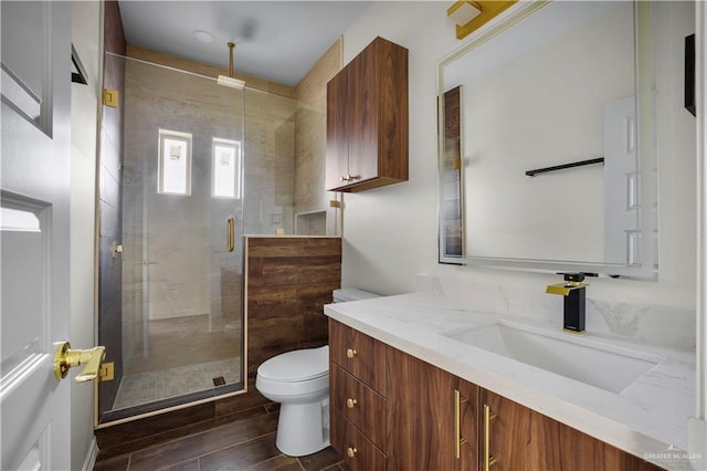 bathroom featuring a shower with door, vanity, and toilet