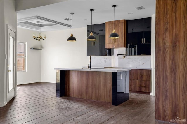 kitchen with sink, a kitchen breakfast bar, dark hardwood / wood-style flooring, an island with sink, and pendant lighting