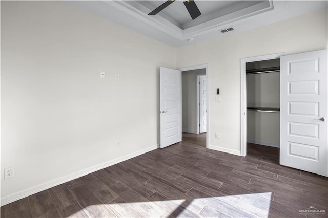 unfurnished bedroom featuring ceiling fan, a raised ceiling, and a closet