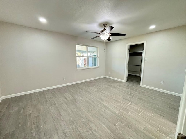 unfurnished bedroom featuring a spacious closet, ceiling fan, and light wood-type flooring