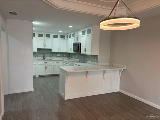 kitchen with kitchen peninsula, sink, white cabinets, dark hardwood / wood-style floors, and a breakfast bar area