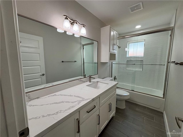 full bathroom with toilet, combined bath / shower with glass door, wood-type flooring, and vanity