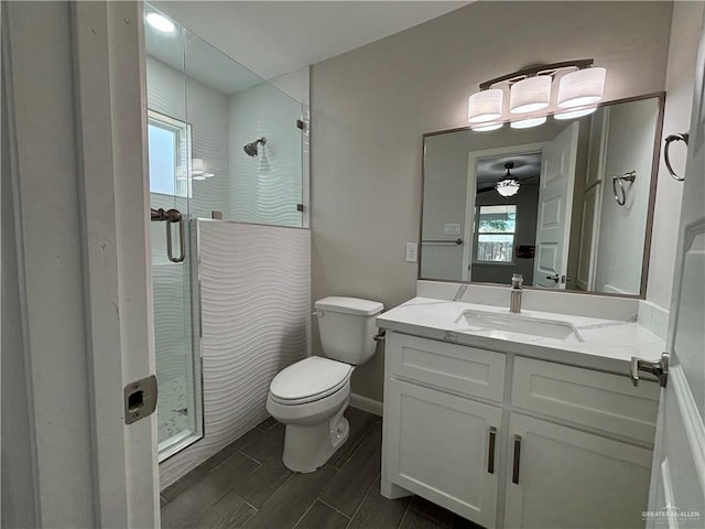 bathroom featuring ceiling fan, toilet, vanity, and walk in shower