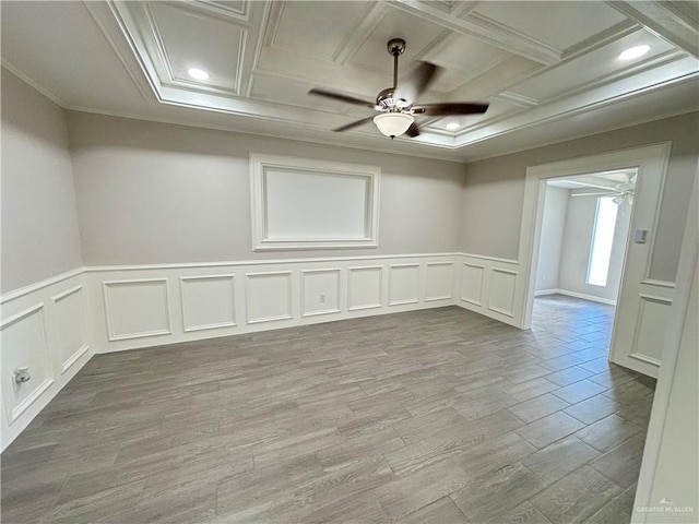 empty room featuring ceiling fan, light wood-type flooring, coffered ceiling, and ornamental molding