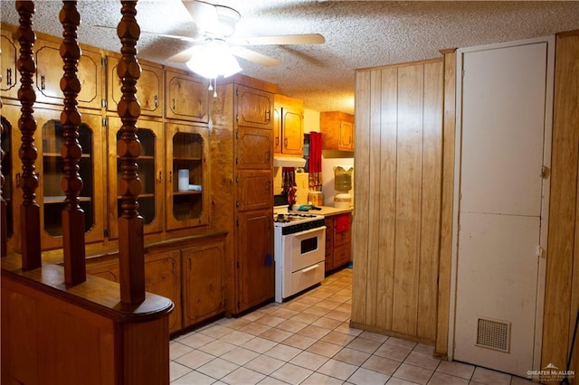 kitchen with light tile patterned floors, ceiling fan, white range oven, and a textured ceiling