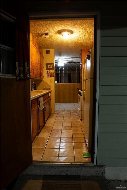 hallway with wood walls, light tile patterned floors, and a textured ceiling