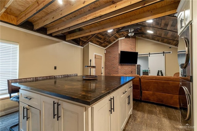 kitchen featuring white cabinetry, dark countertops, stacked washer / dryer, and a barn door