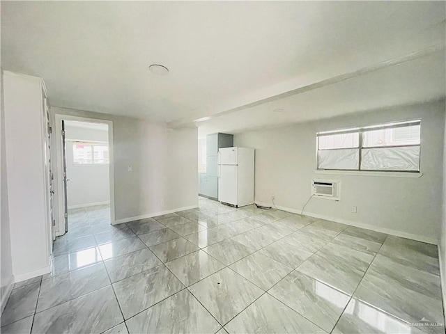 spare room featuring baseboards and an AC wall unit