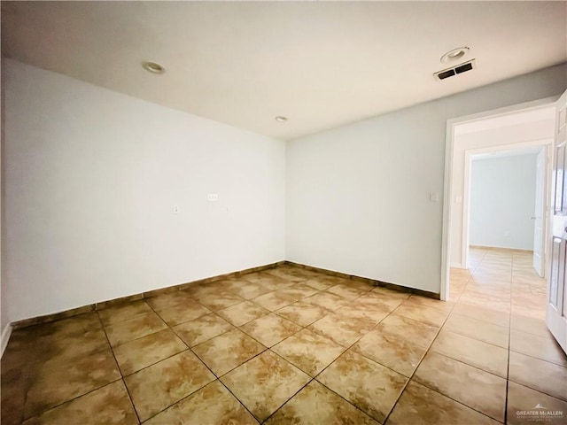 empty room featuring light tile patterned floors, visible vents, and baseboards