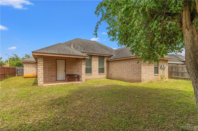 rear view of house featuring a lawn and a patio