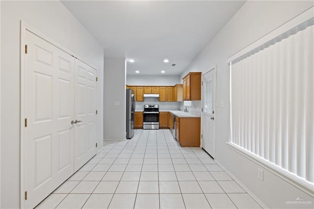 2504 Grayson Ave, Mcallen, TX 78504 - kitchen with appliances with stainless steel finishes, under cabinet range hood, brown cabinetry, light countertops, and light tile patterned floors