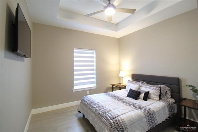 bedroom featuring a raised ceiling, hardwood / wood-style floors, and ceiling fan